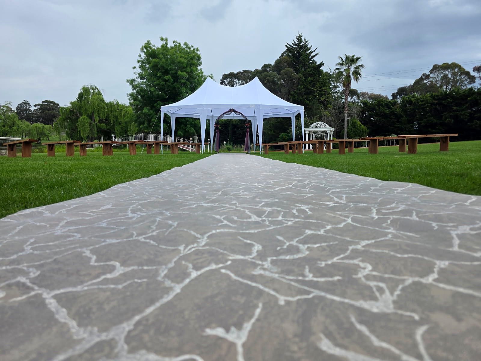 Ceremony aisle with timber benches and a white pavilion